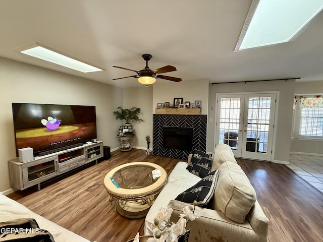 3224 Seabrook St, El Paso, TX 79936 - living room featuring a skylight, wood finished floors, a tile fireplace, a ceiling fan, and baseboards