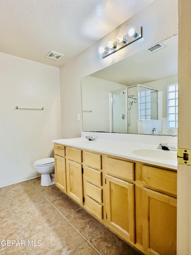 549 Northwyck Way, El Paso, TX 79928 - full bath featuring double vanity, a shower stall, a textured ceiling, tile patterned floors, and toilet