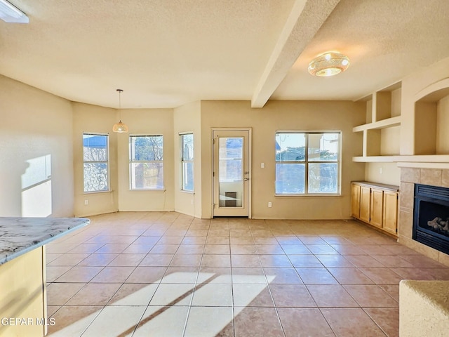 549 Northwyck Way, El Paso, TX 79928 - unfurnished living room with light tile patterned floors, a tile fireplace, a textured ceiling, beam ceiling, and built in features