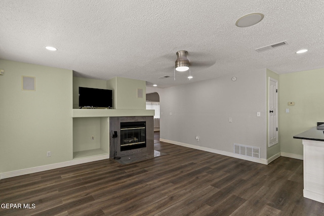 1461 Luz De Luna Pl, El Paso, TX 79912 - unfurnished living room featuring a ceiling fan, dark wood-style floors, a textured ceiling, a tiled fireplace, and baseboards