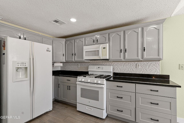 1461 Luz De Luna Pl, El Paso, TX 79912 - kitchen with white appliances, a textured ceiling, dark countertops, and wood finished floors