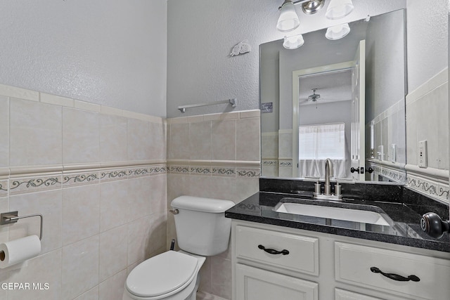 1461 Luz De Luna Pl, El Paso, TX 79912 - bathroom with toilet, tile walls, vanity, a textured wall, and a wainscoted wall