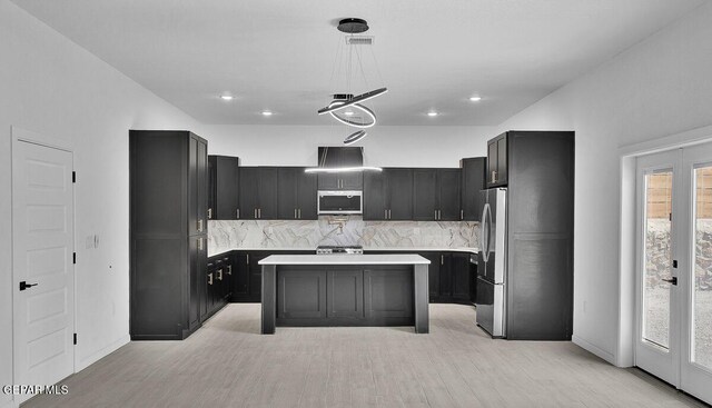 12036 Cotton Cloud Way, Socorro, TX 79927 - kitchen with stainless steel appliances, a kitchen island, tasteful backsplash, light countertops, and dark cabinets