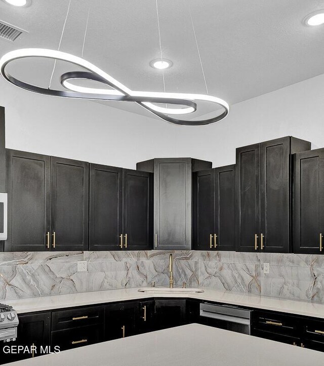 12036 Cotton Cloud Way, Socorro, TX 79927 - kitchen featuring dark cabinets, a sink, stainless steel dishwasher, light countertops, and backsplash