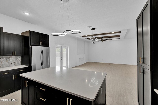12036 Cotton Cloud Way, Socorro, TX 79927 - kitchen with freestanding refrigerator, dark cabinetry, backsplash, hanging light fixtures, and recessed lighting