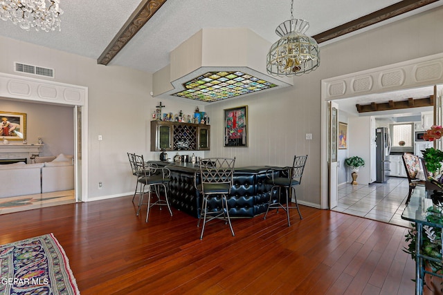 1428 Camino Alto Rd, El Paso, TX 79902 - dining area featuring a chandelier, baseboards, wood finished floors, a textured ceiling, and bar area