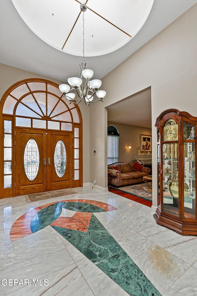 1428 Camino Alto Rd, El Paso, TX 79902 - entrance foyer featuring marble tiled flooring, a chandelier, inlaid floor details, healthy amount of natural light, and a towering ceiling