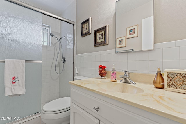 1428 Camino Alto Rd, El Paso, TX 79902 - bathroom with toilet, vanity, a stall shower, tile walls, and wainscoting