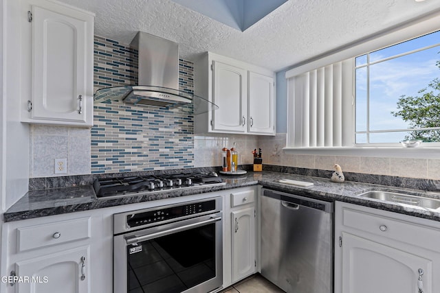1428 Camino Alto Rd, El Paso, TX 79902 - kitchen featuring stainless steel appliances, wall chimney exhaust hood, white cabinetry, tasteful backsplash, and a textured ceiling