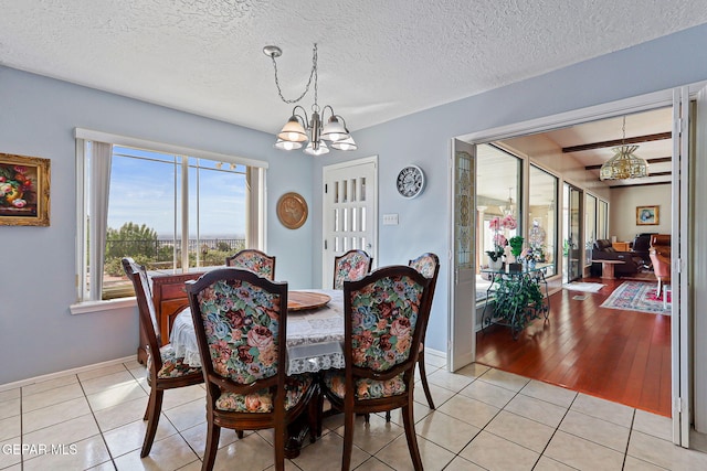 1428 Camino Alto Rd, El Paso, TX 79902 - dining room with a chandelier, light tile patterned flooring, baseboards, and a textured ceiling