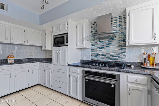 1428 Camino Alto Rd, El Paso, TX 79902 - kitchen featuring stainless steel appliances, wall chimney exhaust hood, white cabinets, light tile patterned floors, and backsplash