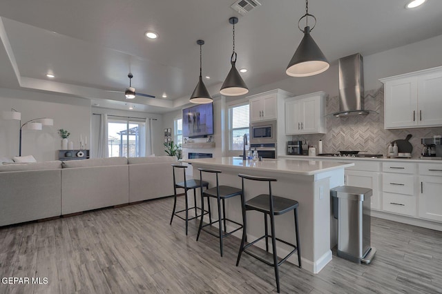 289 Hunstanton St, Horizon City, TX 79928 - kitchen featuring wall chimney exhaust hood, open floor plan, stainless steel appliances, a breakfast bar, and tasteful backsplash