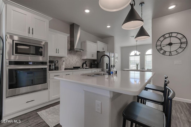 289 Hunstanton St, Horizon City, TX 79928 - kitchen featuring stainless steel appliances, wall chimney exhaust hood, a sink, an island with sink, and light countertops