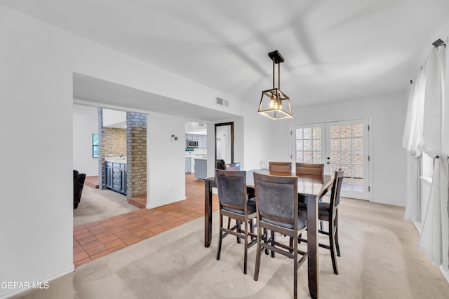 724 Gary Ln, El Paso, TX 79922 - dining space featuring a brick fireplace, light tile patterned floors, light colored carpet, baseboards, and french doors