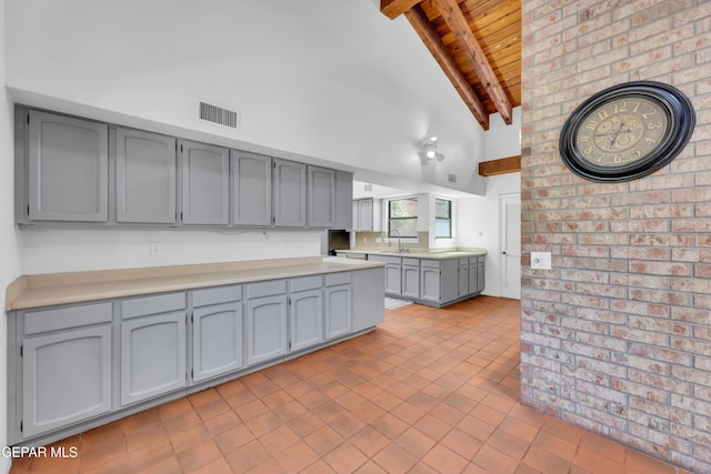 724 Gary Ln, El Paso, TX 79922 - kitchen featuring wood ceiling with exposed beams, gray cabinetry, a sink, light countertops, and light tile patterned floors