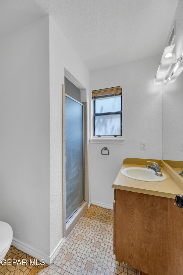 724 Gary Ln, El Paso, TX 79922 - bathroom featuring vanity, a stall shower, baseboards, and toilet