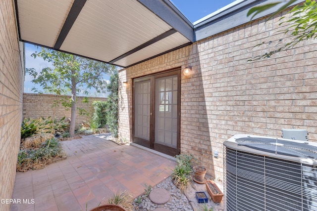 724 Gary Ln, El Paso, TX 79922 - view of exterior entry with french doors, central AC, a patio area, and brick siding