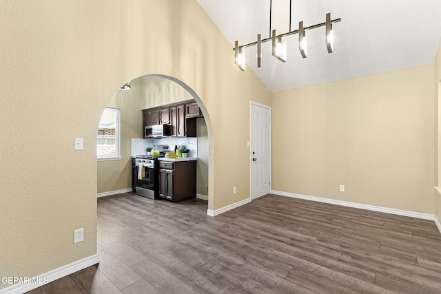 5261 Roger Maris Dr, El Paso, TX 79934 - unfurnished living room featuring arched walkways, dark wood-style floors, baseboards, and high vaulted ceiling