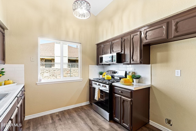 5261 Roger Maris Dr, El Paso, TX 79934 - kitchen with stainless steel appliances, dark brown cabinetry, decorative backsplash, light countertops, and wood finished floors
