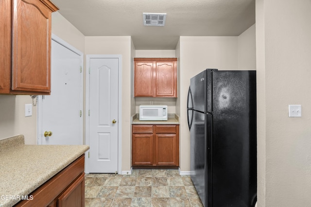 7009 Falling Leaf Cir, El Paso, TX 79934 - kitchen featuring freestanding refrigerator, white microwave, light countertops, and baseboards