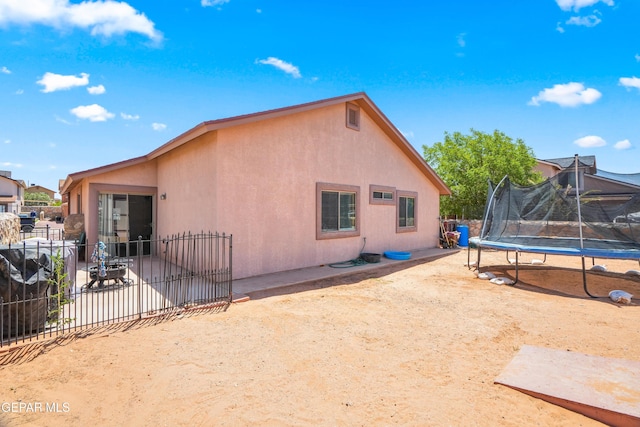 7009 Falling Leaf Cir, El Paso, TX 79934 - back of house with a trampoline, stucco siding, and a patio area