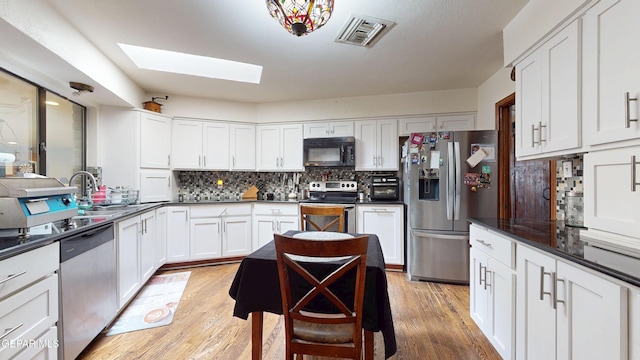 492 Country Oaks Dr, El Paso, TX 79932 - kitchen featuring appliances with stainless steel finishes, a skylight, backsplash, white cabinetry, and dark countertops