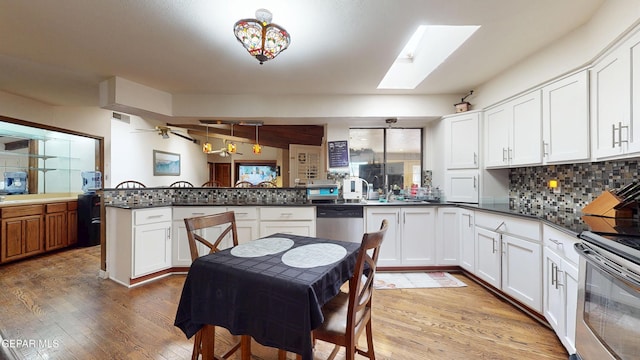 492 Country Oaks Dr, El Paso, TX 79932 - kitchen with a peninsula, appliances with stainless steel finishes, light wood-type flooring, and dark countertops