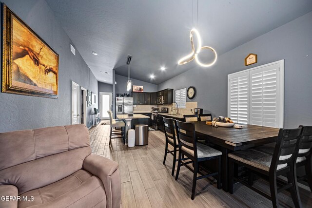 12805 Epsom Dr, Horizon City, TX 79928 - dining area with light wood-type flooring, lofted ceiling, and a textured wall