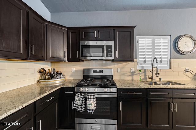 12805 Epsom Dr, Horizon City, TX 79928 - kitchen featuring appliances with stainless steel finishes, a sink, tasteful backsplash, and light stone counters