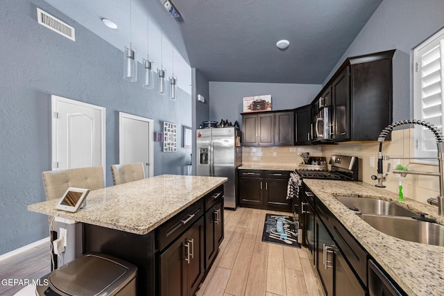 12805 Epsom Dr, Horizon City, TX 79928 - kitchen featuring appliances with stainless steel finishes, a sink, light wood-style floors, a textured wall, and tasteful backsplash