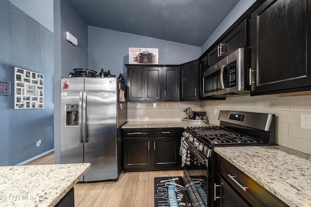 12805 Epsom Dr, Horizon City, TX 79928 - kitchen featuring appliances with stainless steel finishes, light wood finished floors, lofted ceiling, and decorative backsplash