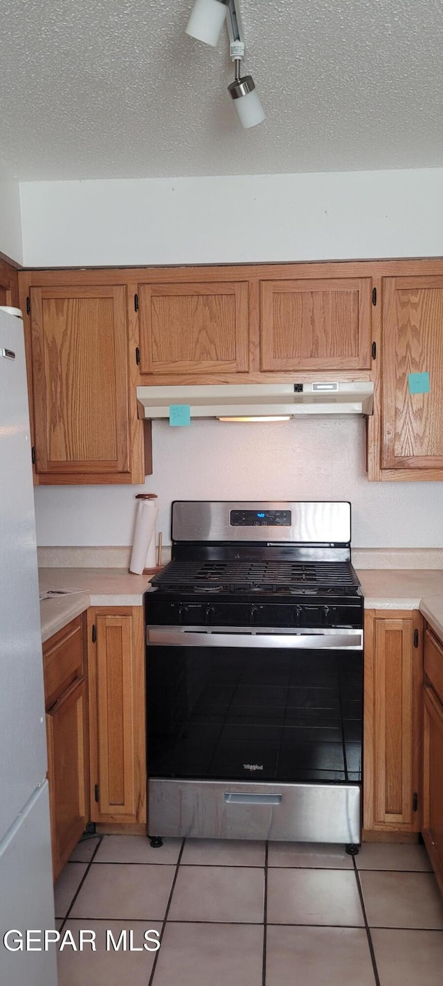 5121 Orleans Ave, El Paso, TX 79924 - kitchen with appliances with stainless steel finishes, light countertops, light tile patterned flooring, under cabinet range hood, and a textured ceiling