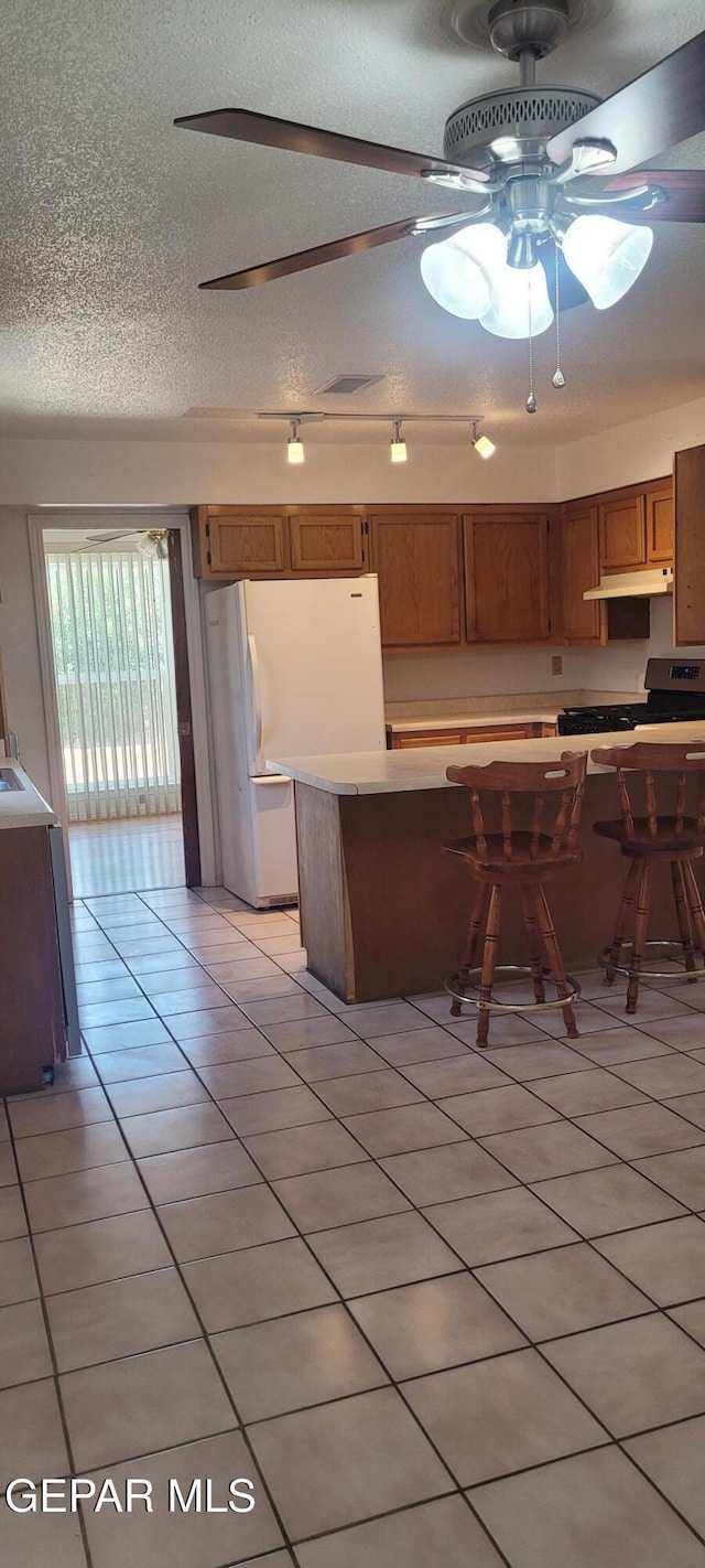 5121 Orleans Ave, El Paso, TX 79924 - kitchen with light tile patterned floors, ceiling fan, a textured ceiling, stainless steel range, and brown cabinetry
