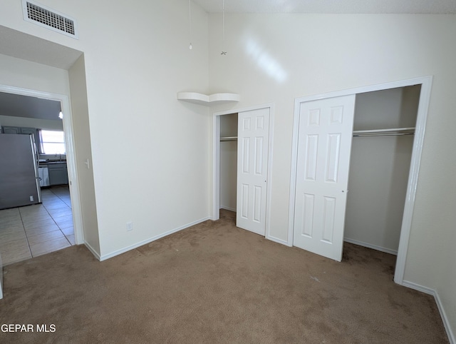 11740 Autumn Wheat Dr, El Paso, TX 79934 - unfurnished bedroom with freestanding refrigerator, carpet, multiple closets, baseboards, and a towering ceiling