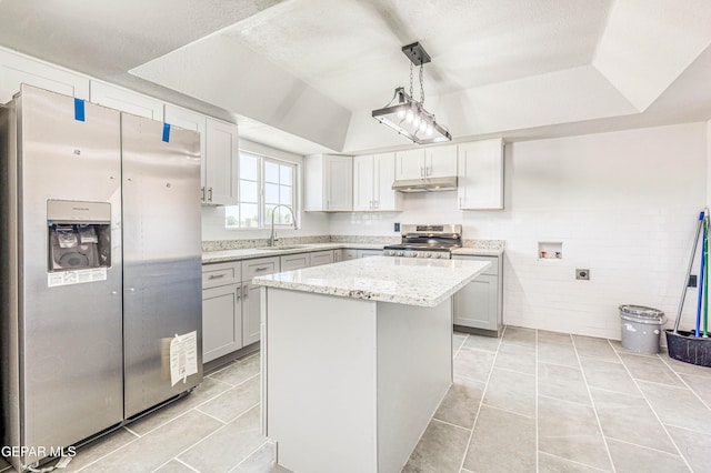 13090 Socorro Rd, San Elizario, TX 79849 - kitchen with stainless steel appliances, under cabinet range hood, a sink, light tile patterned floors, and vaulted ceiling