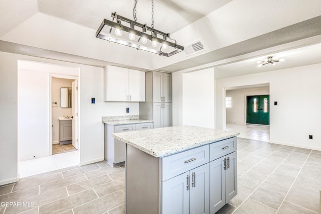 13090 Socorro Rd, San Elizario, TX 79849 - kitchen with light tile patterned flooring, baseboards, light stone countertops, a kitchen island, and gray cabinetry