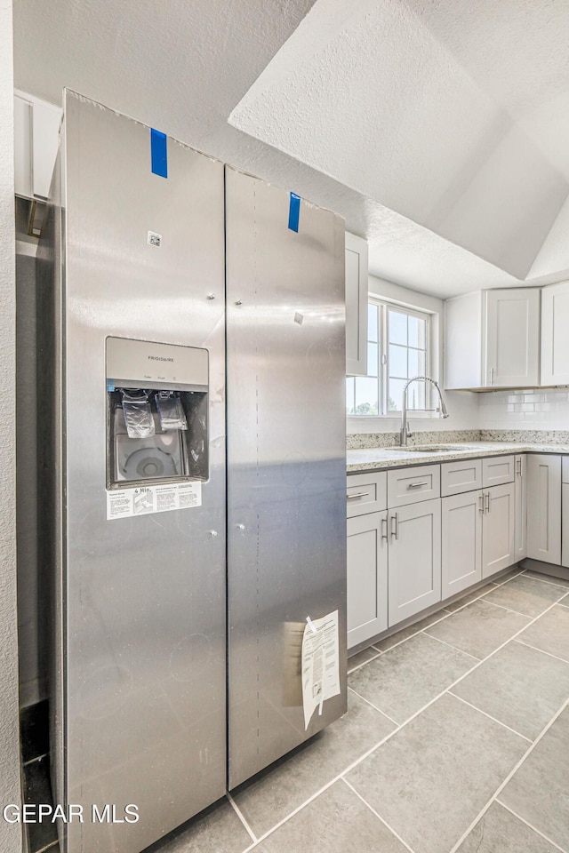13090 Socorro Rd, San Elizario, TX 79849 - kitchen with a sink, a textured ceiling, light tile patterned floors, and light stone countertops