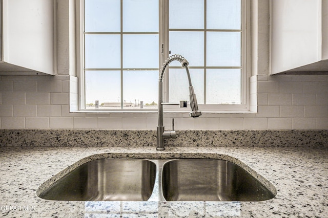 13090 Socorro Rd, San Elizario, TX 79849 - kitchen view of a sink, white cabinetry, decorative backsplash, and light stone countertops