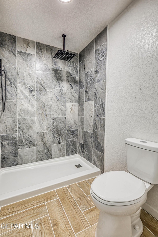 13090 Socorro Rd, San Elizario, TX 79849 - full bathroom featuring toilet, tiled shower, a textured ceiling, and wood finished floors