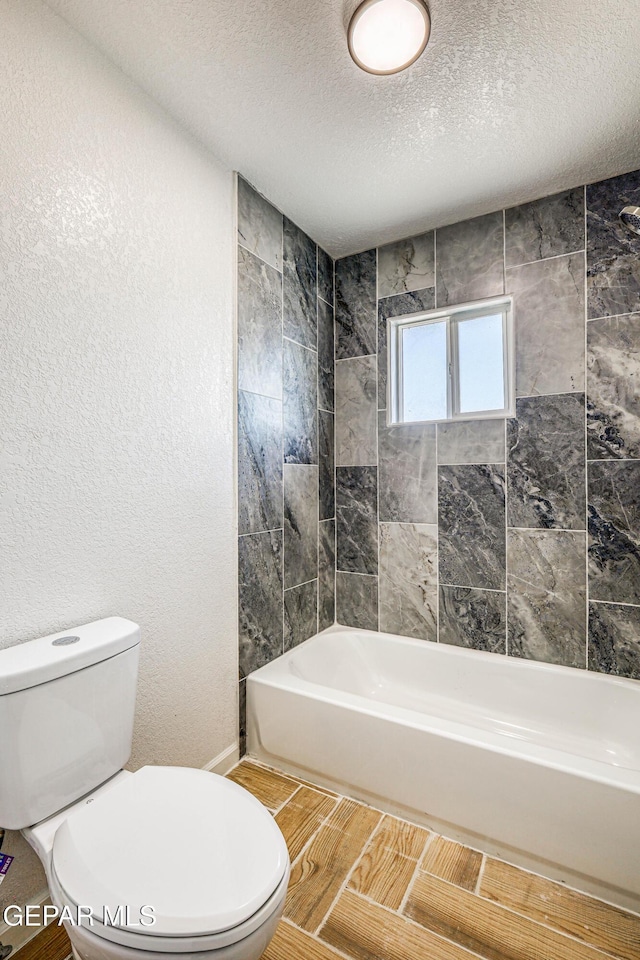 13090 Socorro Rd, San Elizario, TX 79849 - full bath with toilet, wood tiled floors, shower / washtub combination, a textured ceiling, and a textured wall