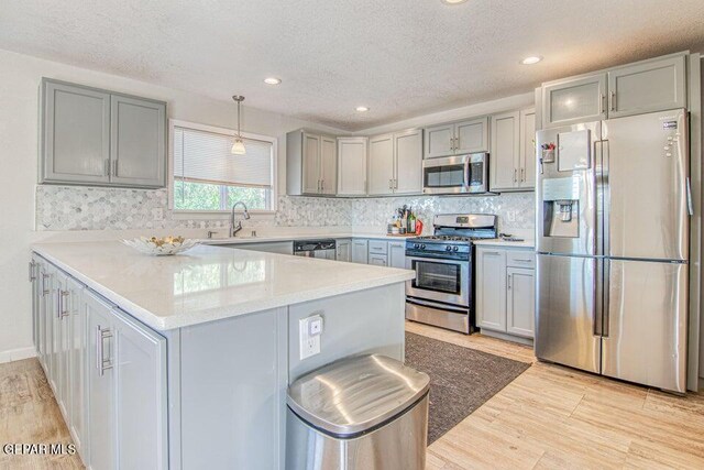 6504 Camino Fuente Dr, El Paso, TX 79912 - kitchen with stainless steel appliances, gray cabinets, a textured ceiling, a peninsula, and light wood finished floors