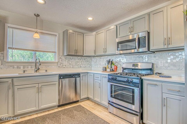 6504 Camino Fuente Dr, El Paso, TX 79912 - kitchen with appliances with stainless steel finishes, a sink, a textured ceiling, gray cabinets, and light countertops
