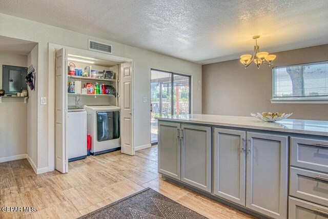 6504 Camino Fuente Dr, El Paso, TX 79912 - kitchen with independent washer and dryer, gray cabinets, a chandelier, light wood finished floors, and a textured ceiling