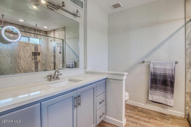 6504 Camino Fuente Dr, El Paso, TX 79912 - bathroom with wood finished floors, toilet, vanity, a shower stall, and baseboards