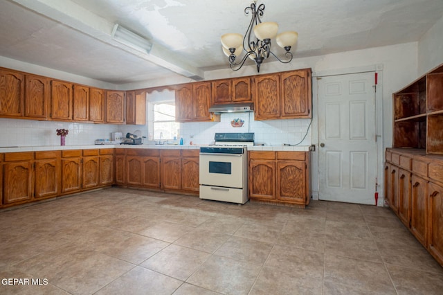 363 Ontiveros St, El Paso, TX 79932 - kitchen featuring gas range gas stove, under cabinet range hood, brown cabinets, backsplash, and beam ceiling
