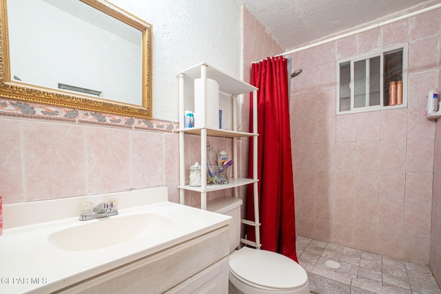 363 Ontiveros St, El Paso, TX 79932 - bathroom with tiled shower, a textured ceiling, toilet, vanity, and tile walls