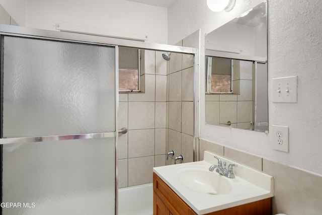 1611 N Kansas St, El Paso, TX 79902 - full bath with vanity, bath / shower combo with glass door, tasteful backsplash, a textured wall, and toilet