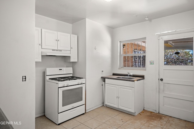 1611 N Kansas St, El Paso, TX 79902 - kitchen with white gas range oven, under cabinet range hood, a sink, white cabinets, and light tile patterned flooring
