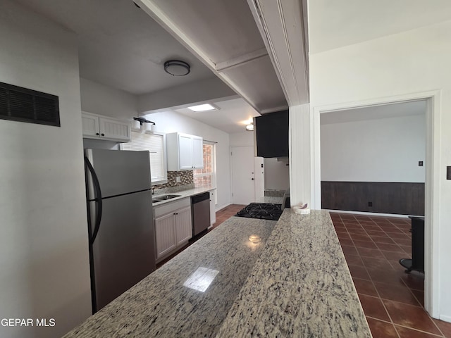 5121 Juliandra Ave, El Paso, TX 79924 - kitchen featuring appliances with stainless steel finishes, light stone counters, dark tile patterned floors, backsplash, and a sink