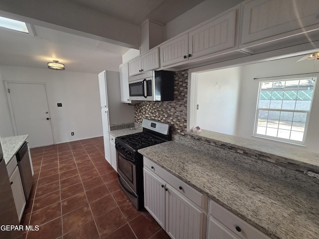 5121 Juliandra Ave, El Paso, TX 79924 - kitchen featuring appliances with stainless steel finishes, backsplash, white cabinetry, dark tile patterned flooring, and light stone countertops